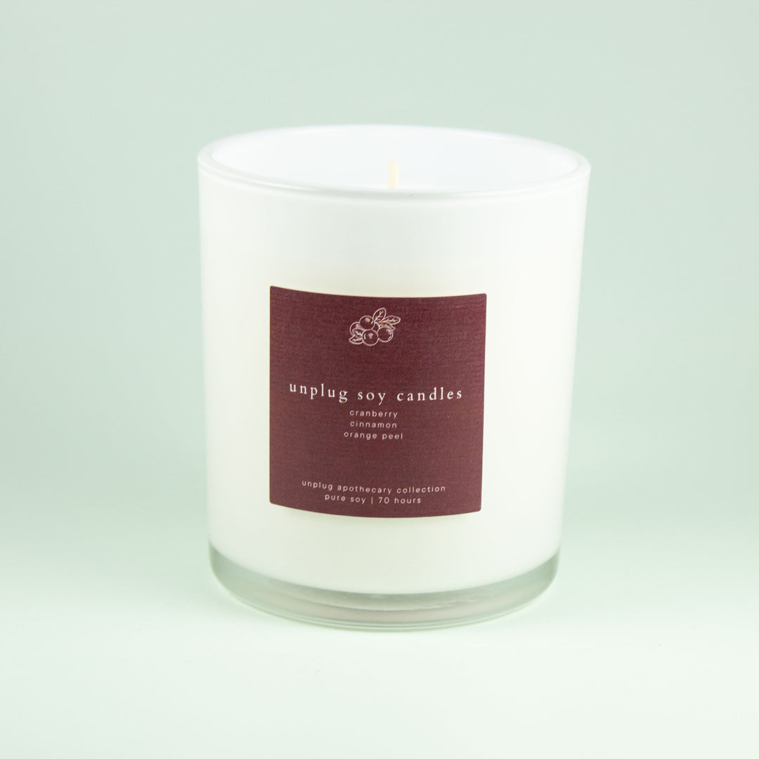 White soy candle candle with a maroon label on a light green background