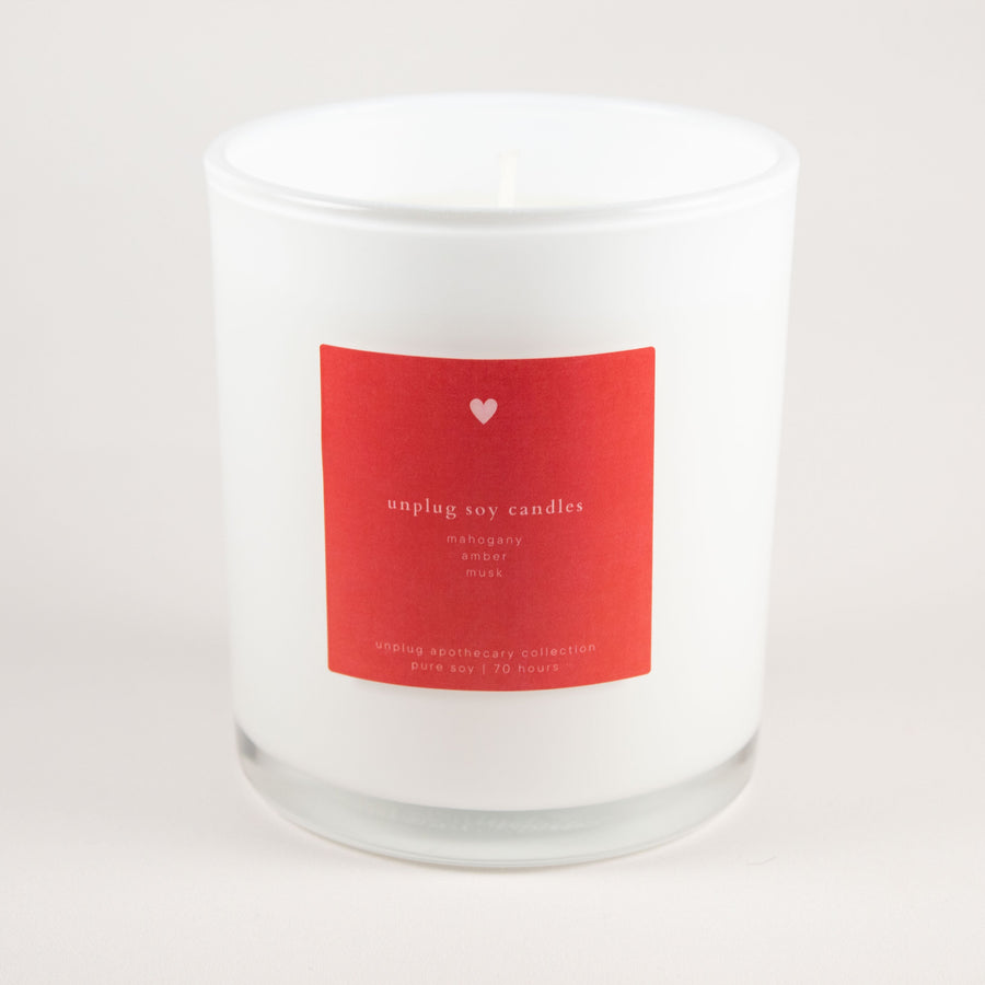 White candle with a red label on a light gray background