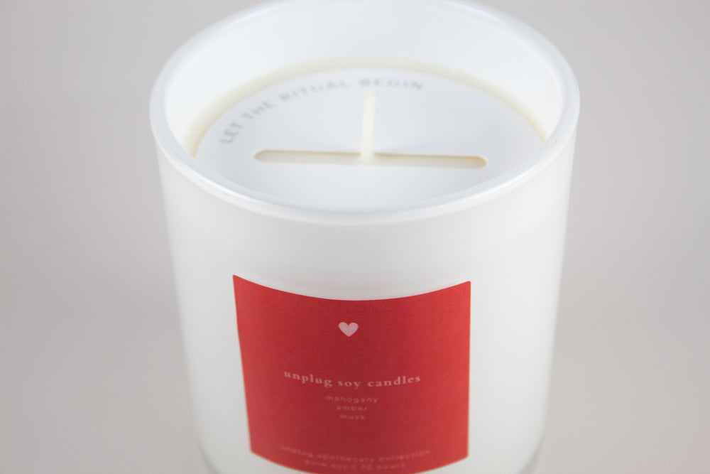 White candle with a red label on a light gray background