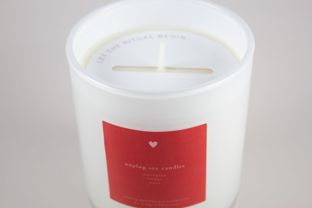 White candle with a red label on a light gray background