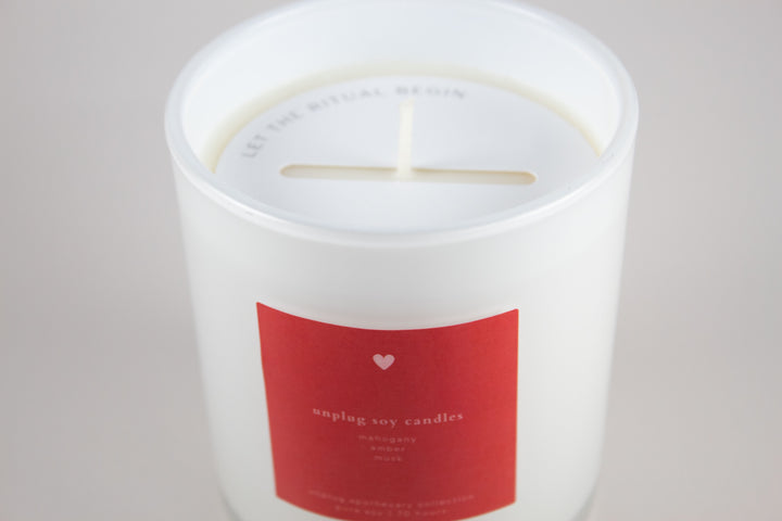 White candle with a red label on a light gray background
