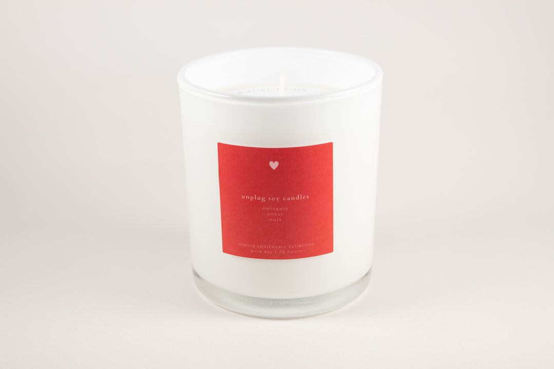 White candle with a red label on a light gray background