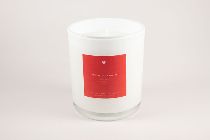White candle with a red label on a light gray background