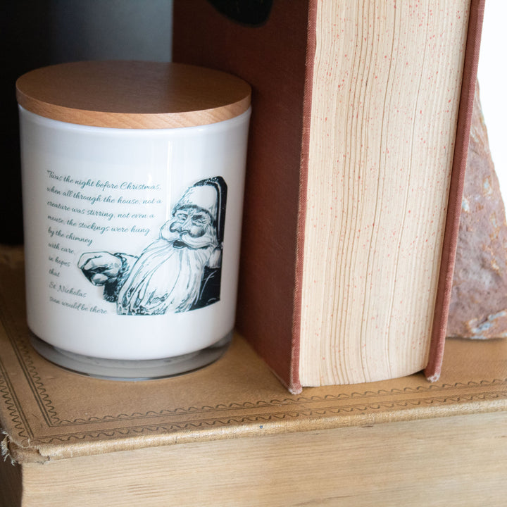 Candle with a printed design on a wooden surface next to an open book